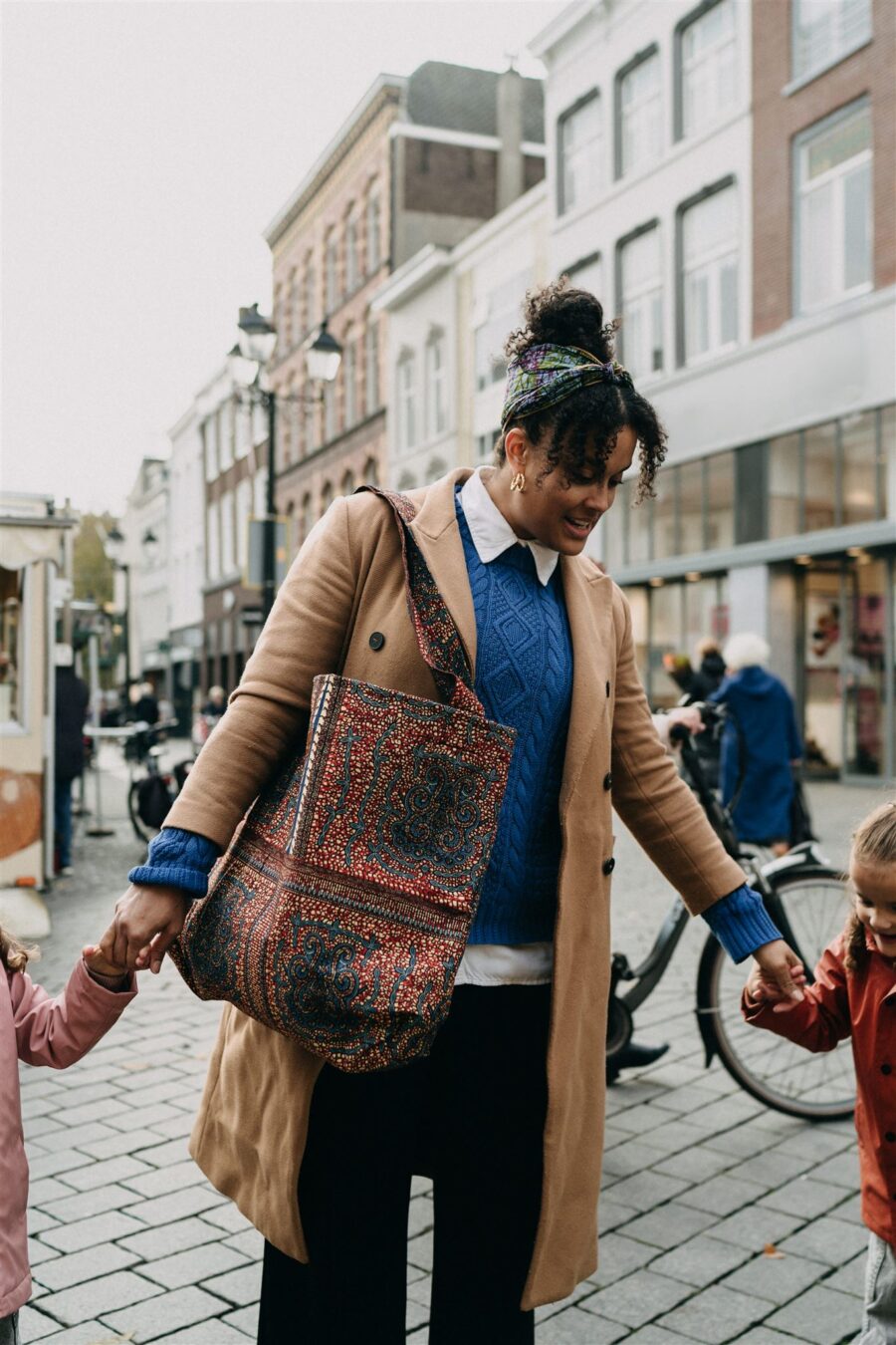 Vrouw loopt door de stad en draagt de etatoua tas over haar schouder